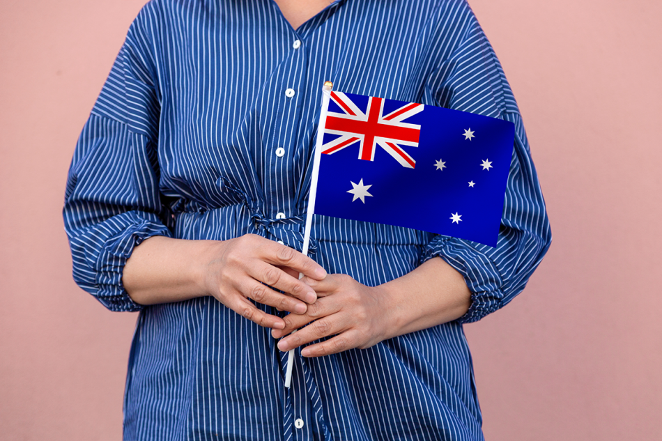 Australia flag. Close up of a woman's hands holding Australian flag - Emigrate2